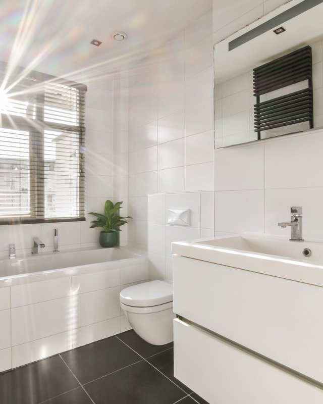 A clean bright bathroom in Hoboken, NJ featuring a hanging toilet and tub.