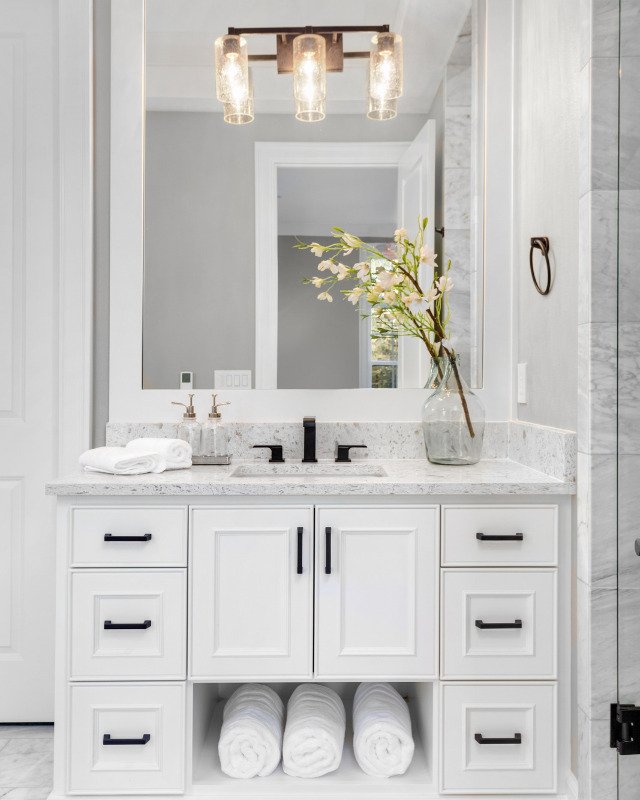 An ethereal bathroom interior in a luxury home in Hoboken, NJ, graced with a pristine white vanity, a resplendent mirror, and luminous gold lighting, creating an ambiance of opulence and tranquility, a masterpiece of design by Hoboken Bathroom Renovation.