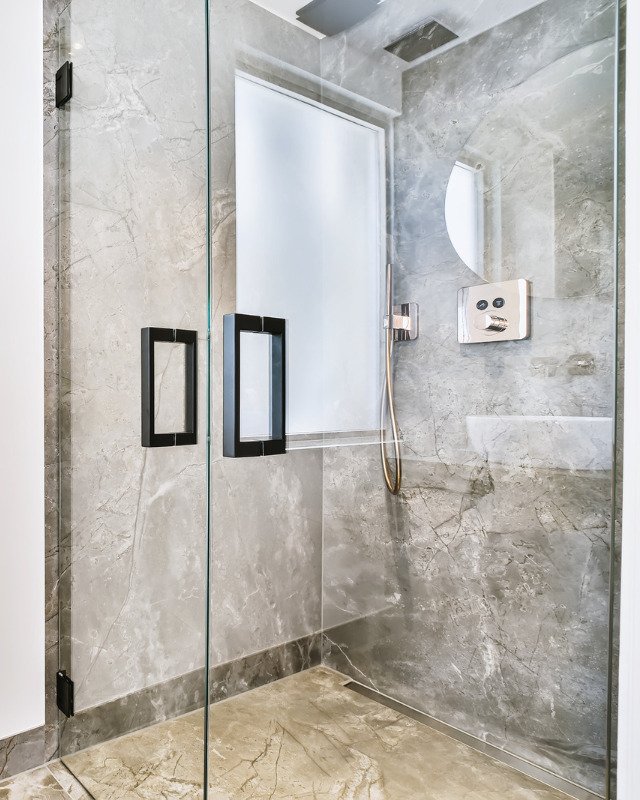 Luxury shower remodel in Secaucus, NJ featuring a large glass enclosed shower and elegant marble tile walls.